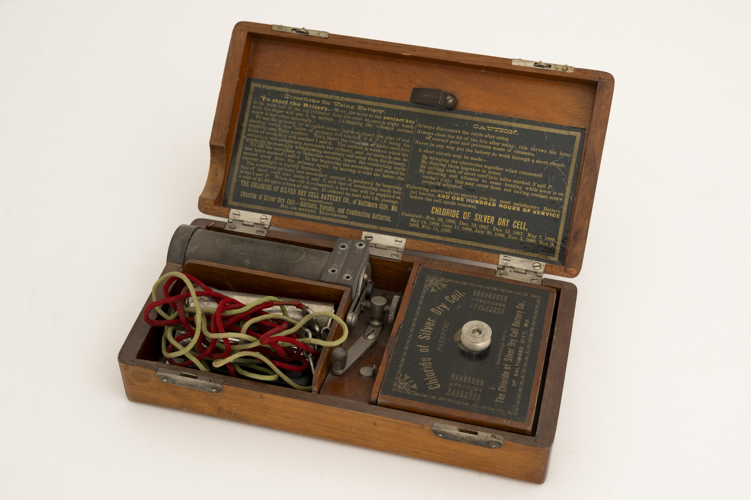 Open wooden box containing battery and accessories for use.